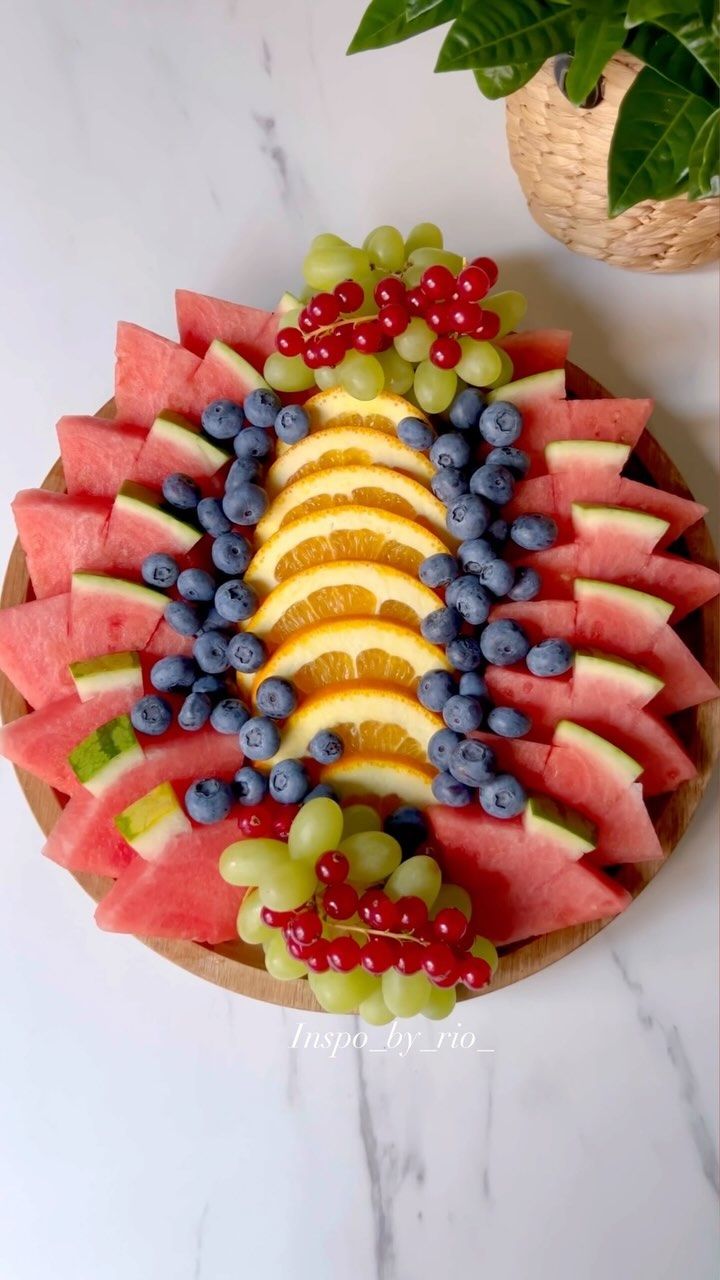 a platter with watermelon, blueberries, oranges and grapes on it