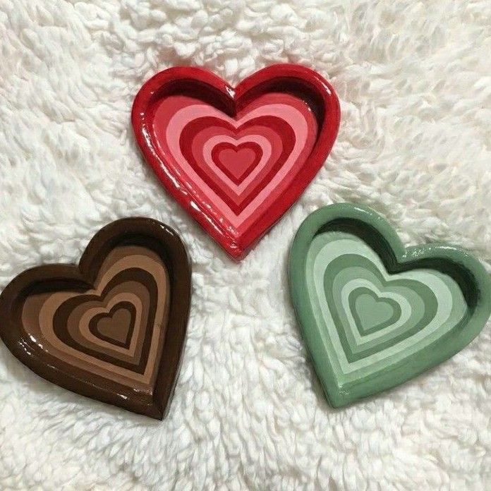 three heart shaped trays sitting on top of a white blanket