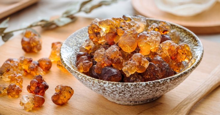 a bowl filled with lots of brown and yellow candies on top of a wooden cutting board