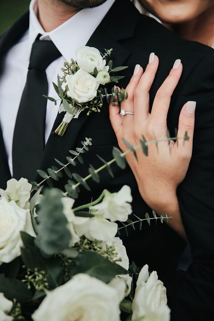 a close up of a person wearing a suit and holding flowers