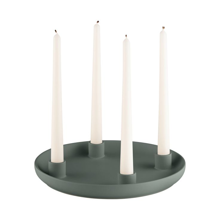 four white candles sitting on top of a gray plate with one candle in the middle