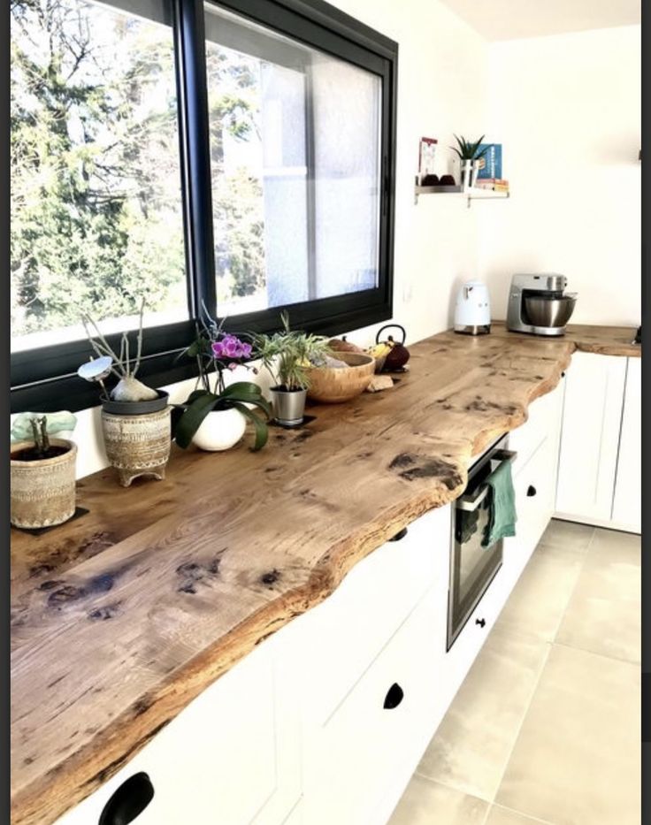 a kitchen counter with pots and pans on it, in front of a window