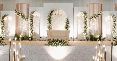 a wedding ceremony setup with white flowers and greenery on the wall, along with candles