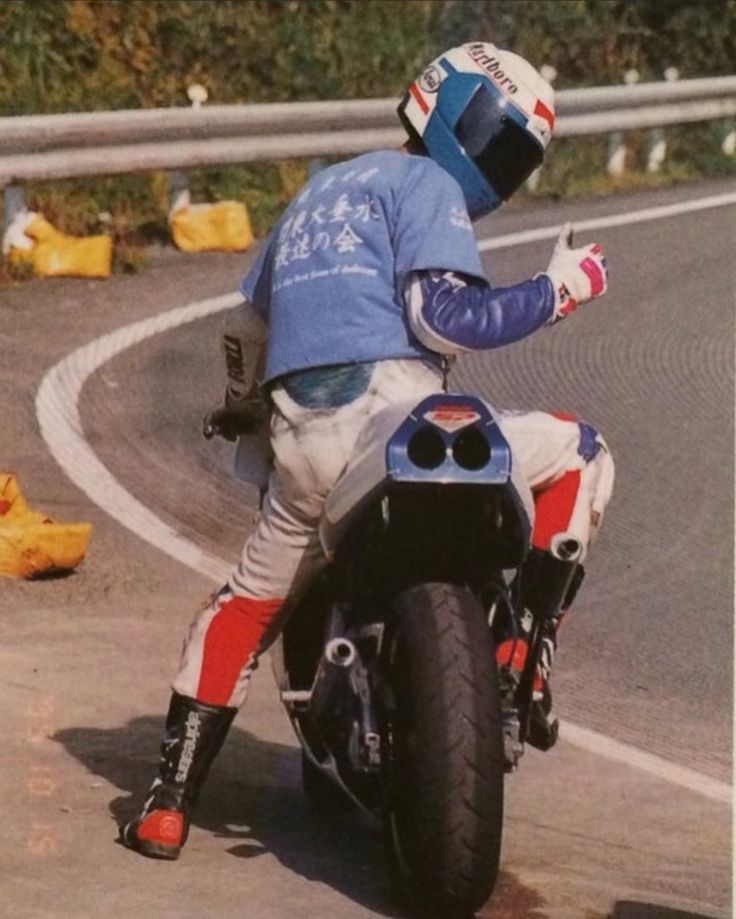 a man riding on the back of a motorcycle down a curvy road