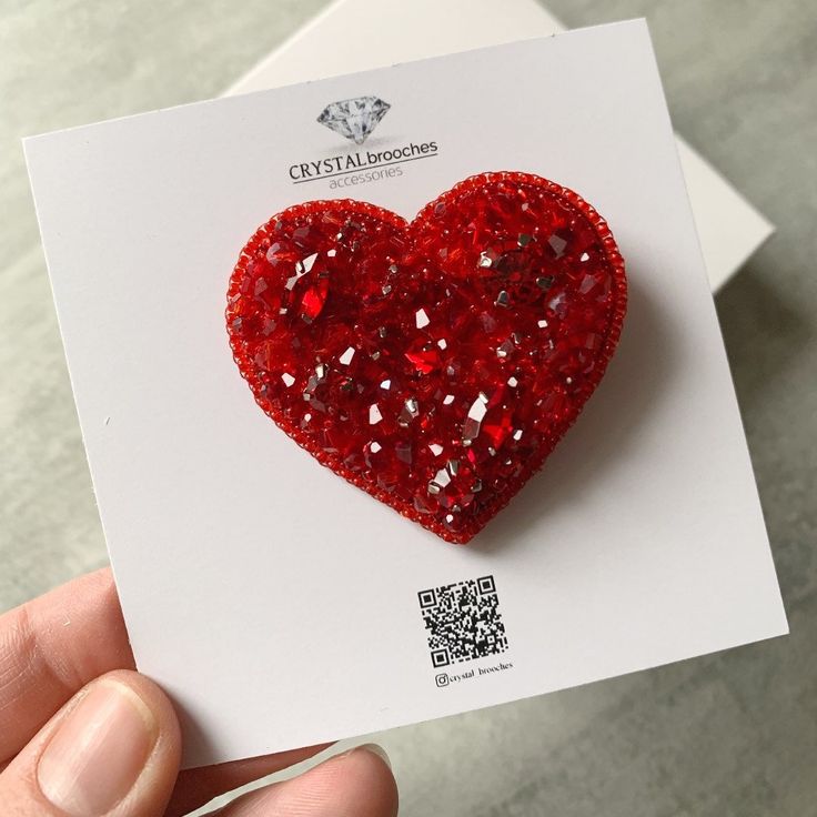 a red heart shaped brooch sitting on top of a piece of paper