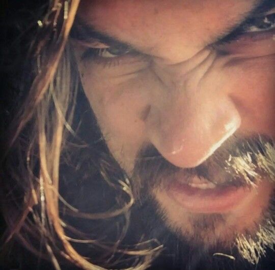 a man with long hair and beard looking down