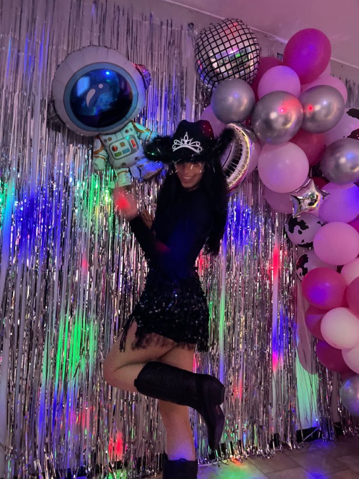 a woman standing in front of balloons and streamers