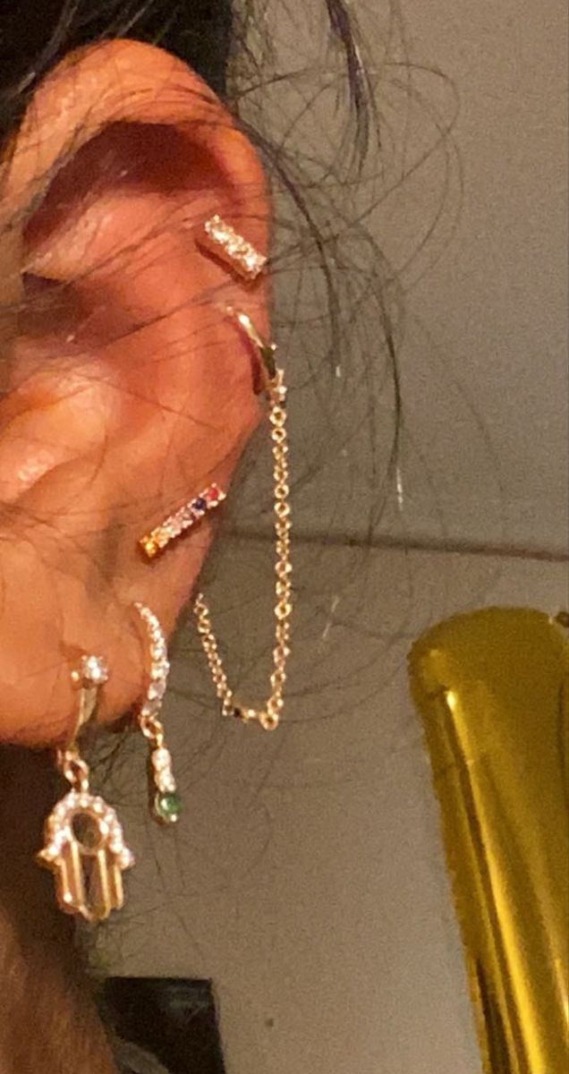 a person with ear piercings on their ears and wearing gold chains around the ears