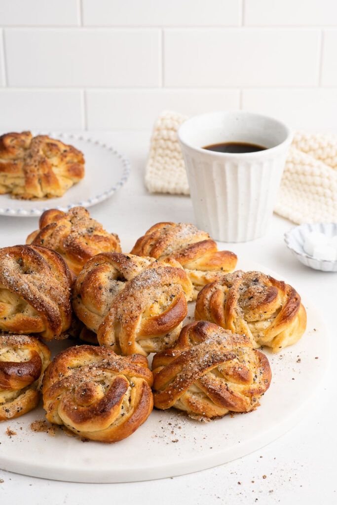 a white plate topped with cinnamon rolls next to a cup of coffee and napkins