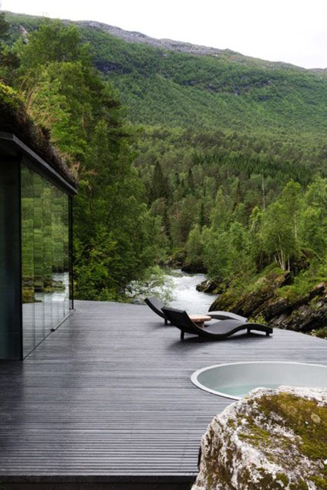 an outdoor hot tub in front of a scenic mountain view with a river running through it