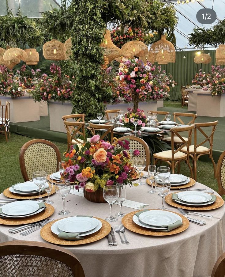 a table set with plates and place settings for an outdoor dinner in a garden setting