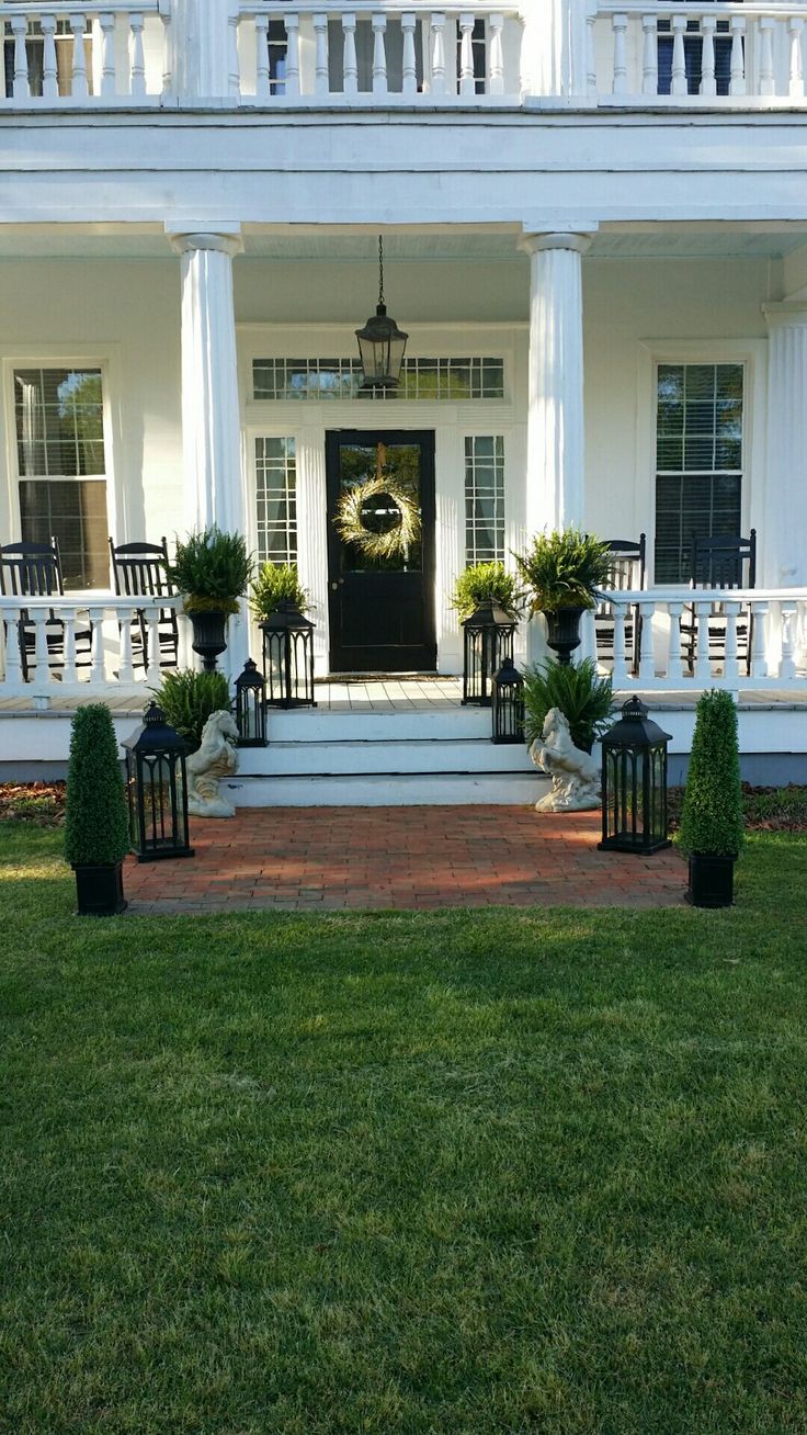 the front porch of a large white house with columns and wreaths on it's pillars