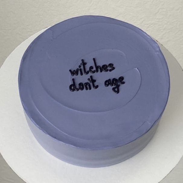 a blue cake with writing on it that says witches don't age