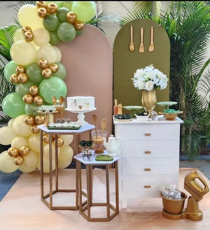 two tables with desserts on them in front of balloons and greenery at a party