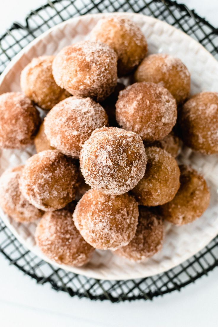 powdered sugar coated donuts in a white bowl on a black and white plate