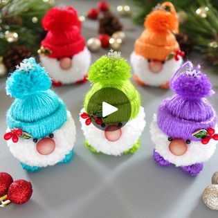 several small knitted hats with pom poms on them and christmas decorations in the background