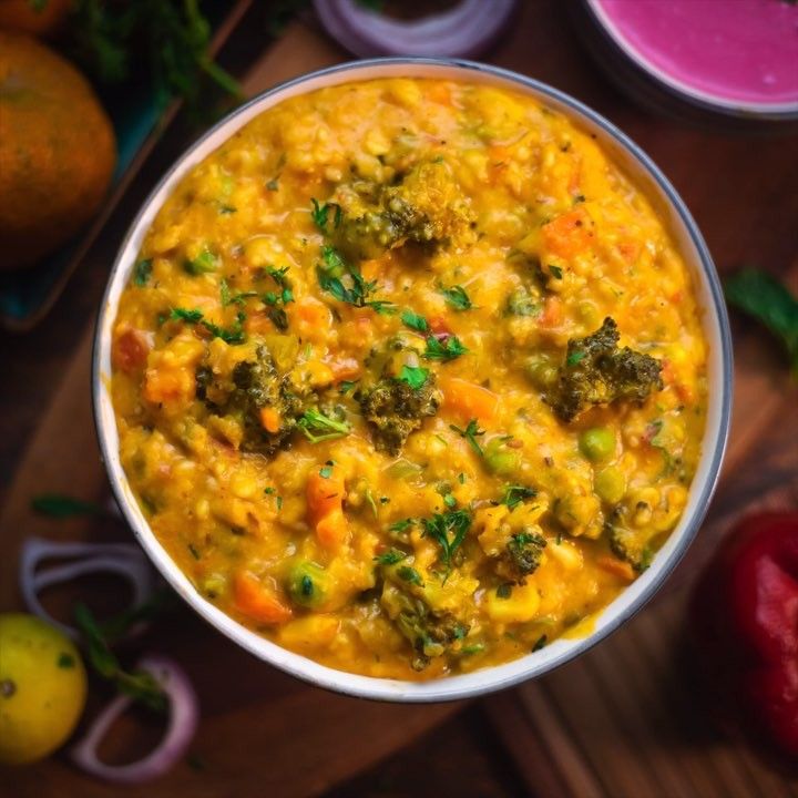 a bowl filled with broccoli and carrots on top of a wooden table