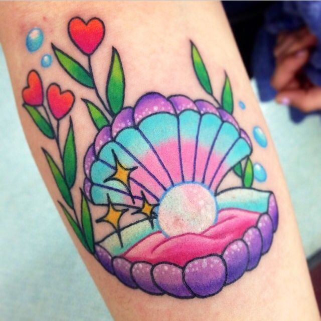 a colorful tattoo on the leg of a woman's arm with an image of a seashell