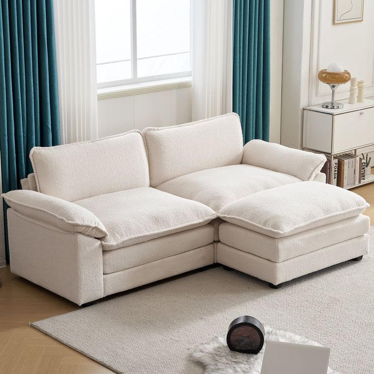 a white couch sitting on top of a rug in a living room next to a window