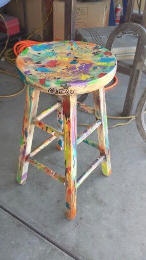 a stool made out of paint sitting on top of a cement floor next to a bike