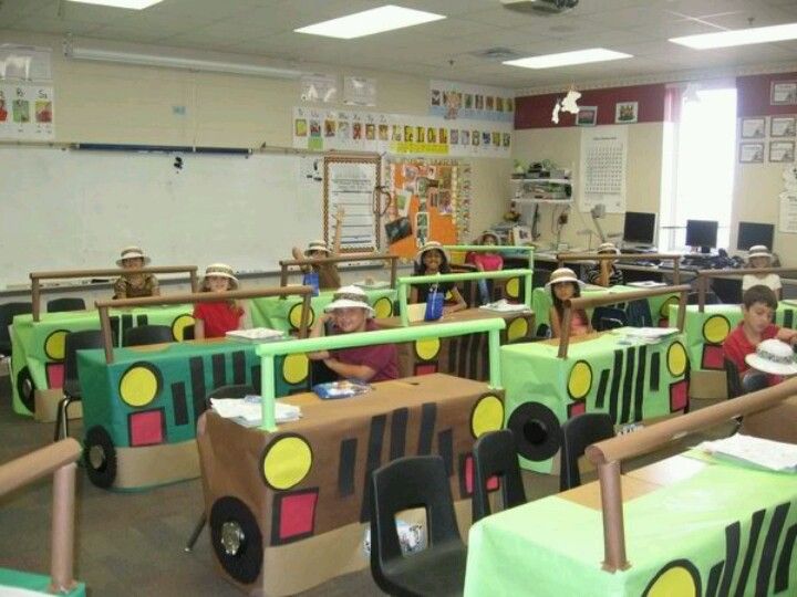 children are sitting at desks made to look like train cars