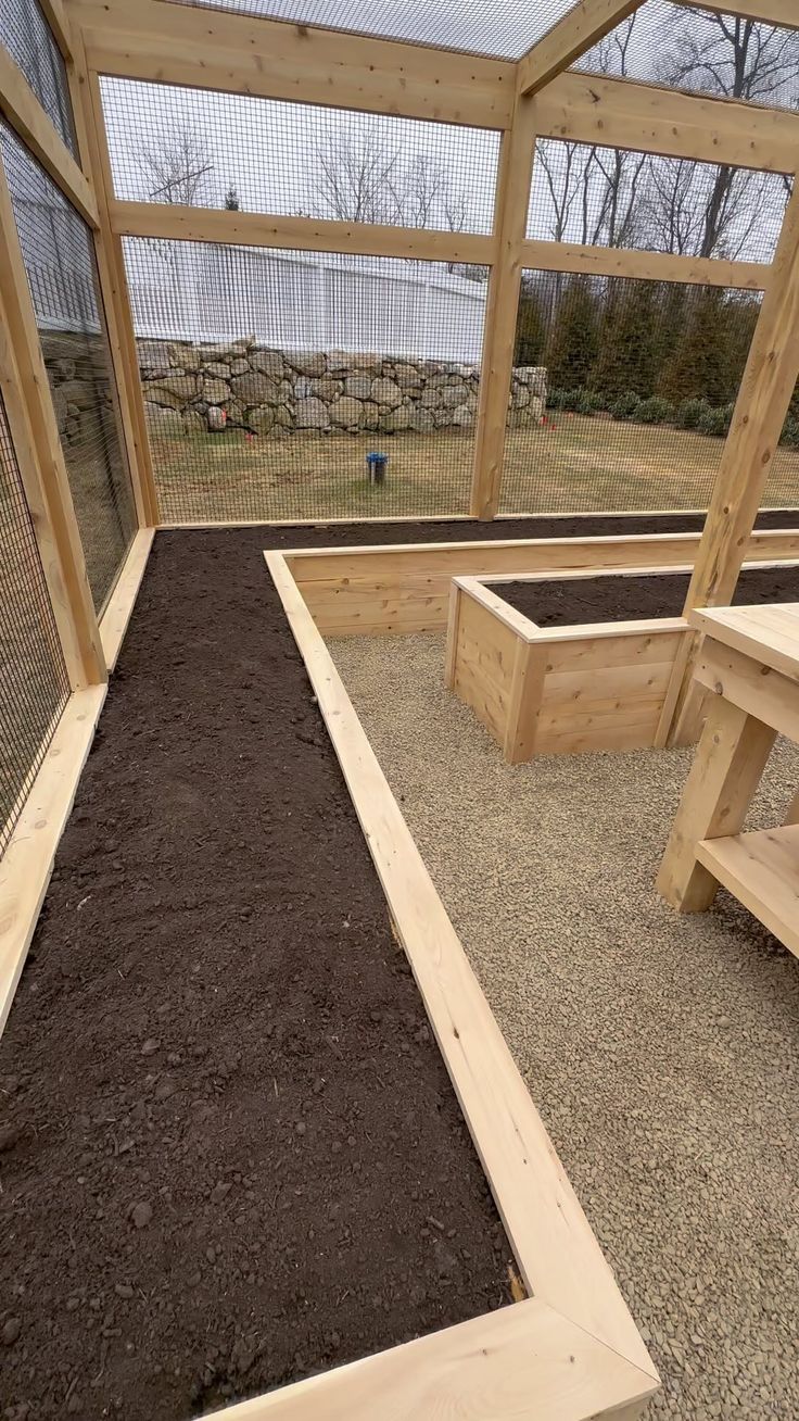 an enclosed area with wooden benches and dirt in the ground next to a rock wall