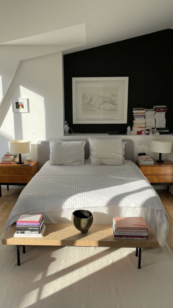 a bed sitting in a bedroom next to a table with books on top of it