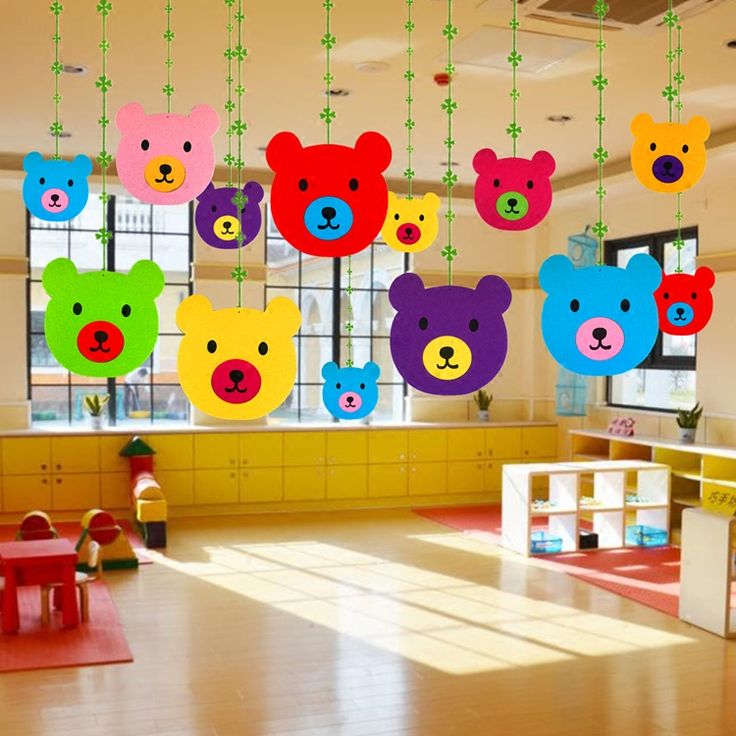 colorful teddy bears hanging from the ceiling in a children's playroom with wooden flooring