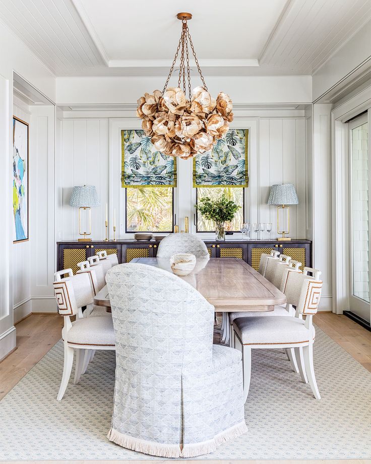 a dining room table with chairs and a chandelier hanging from it's ceiling