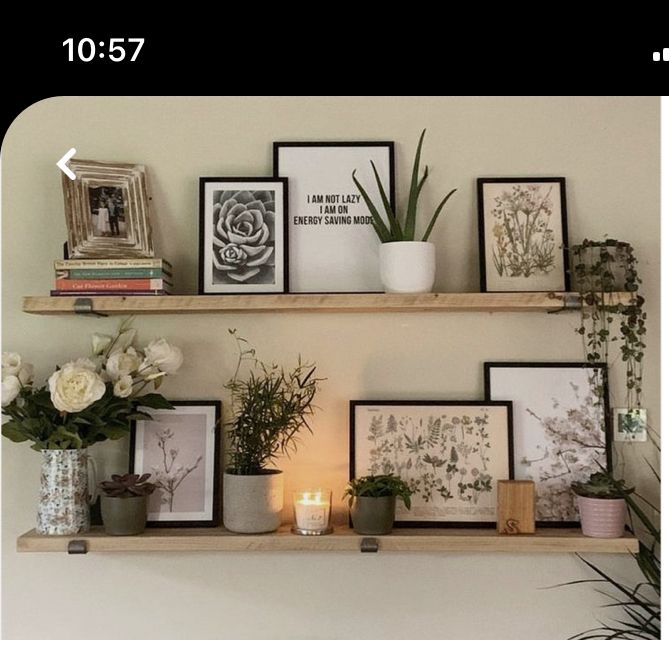 two shelves with pictures, flowers and candles on them in front of a white wall