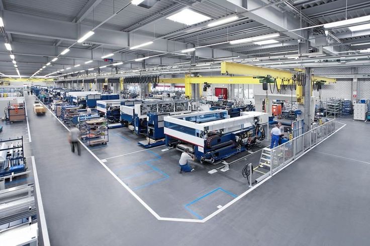 an assembly line in a factory with workers working on machines and equipment inside the building