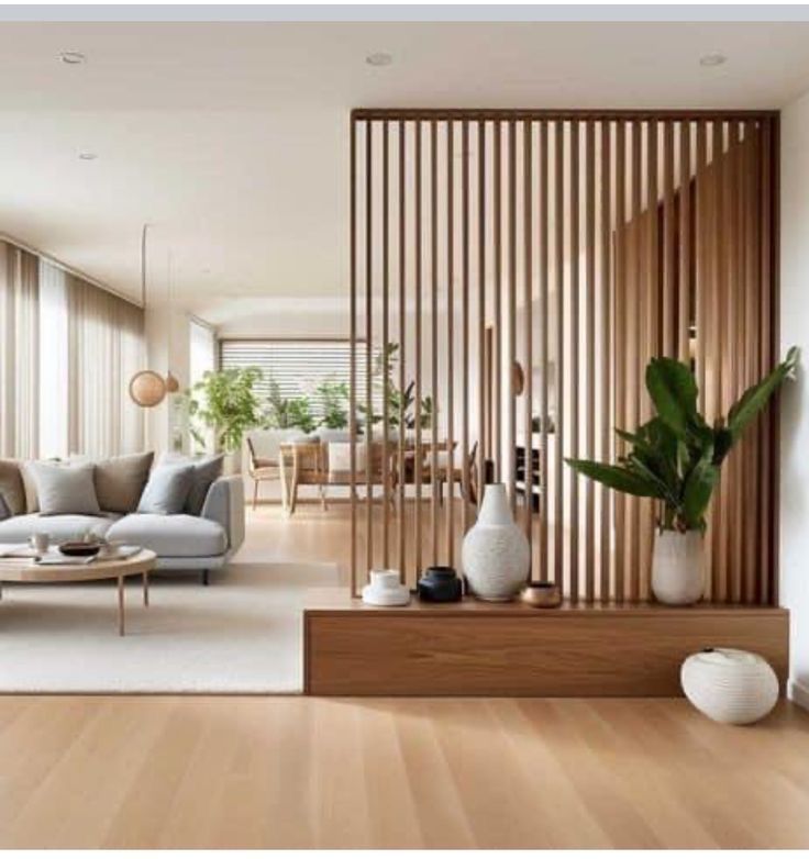 a living room filled with furniture next to a wooden wall covered in plants and potted plants