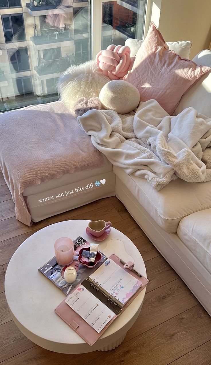 a white couch sitting next to a table on top of a hard wood floor covered in blankets