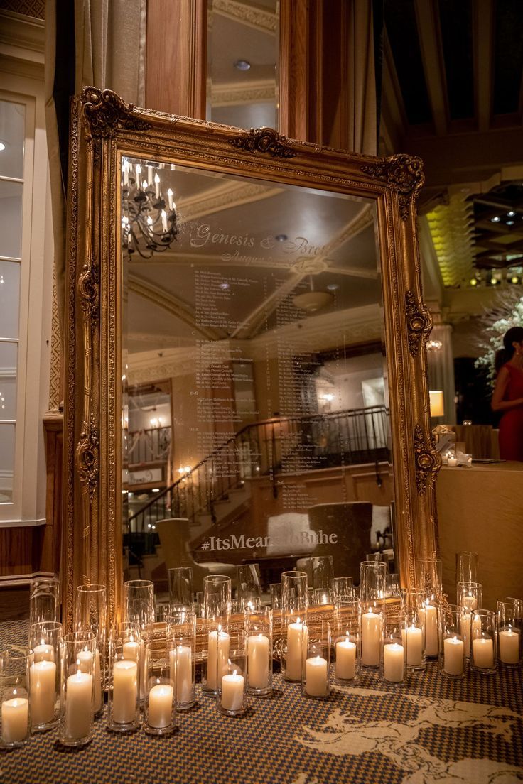 many candles are lit in front of a large mirror