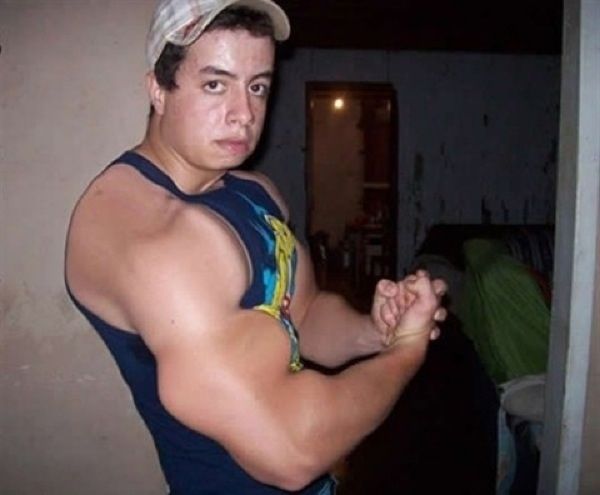 a young man in a tank top is holding his arm out and looking at the camera