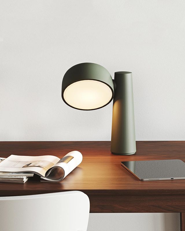 a table lamp sitting on top of a wooden desk next to a laptop and magazine