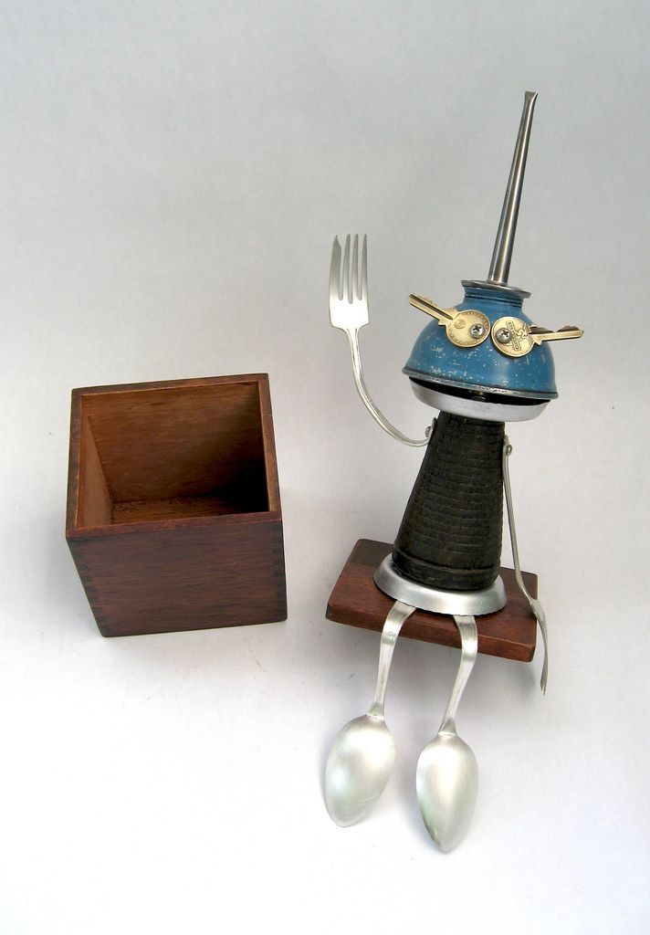 a small figurine with a fork and knife in it's hand next to a wooden box