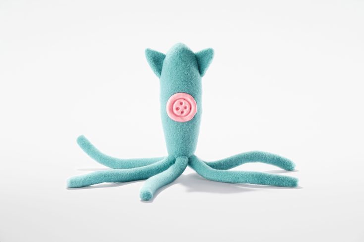 an octopus stuffed animal with a pink button on it's face and legs, sitting upright