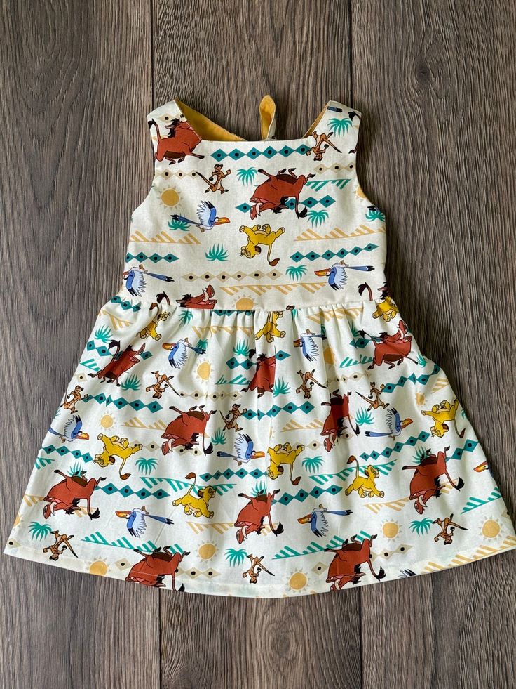 This dress is made from a lightweight and breathable cotton fabric. They have an elastic waist for comfort. making it perfect for the warmer months. It has a modern design with a fun print. Get this adorable dress made of natural cotton today! Playful Cotton Dress For Playwear, Cute Cotton Twirl Dress For Playwear, Playful Cotton Twirl Dress For Playdate, Playful Cotton Twirl Dress For Playtime, Fun Cotton Twirl Dress For Playwear, Playful Cotton Twirl Dress For Play, Summer Cartoon Print Dresses For Playtime, Playful Cotton Twirl Dress, Summer Cartoon Print Dress For Playtime