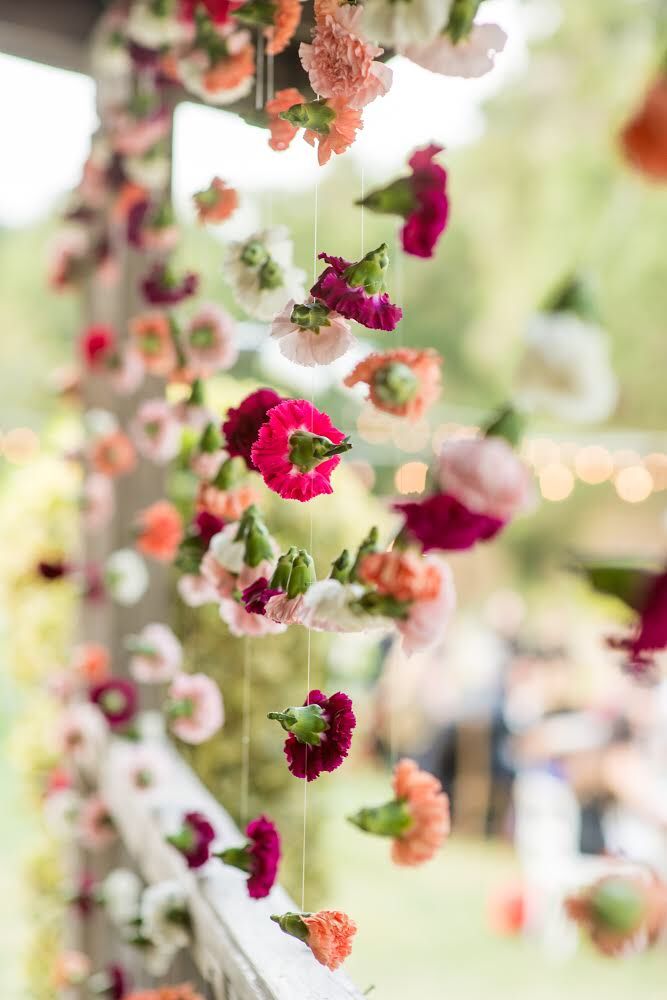 flowers are hanging from the side of a wooden fence with string lights in the background