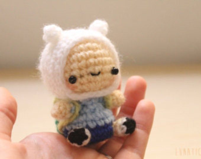 a small crocheted doll is held in someone's hand