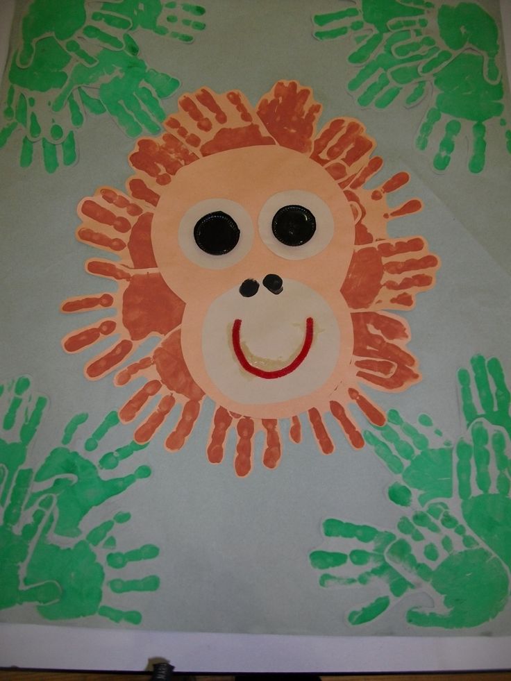 a child's drawing of a monkey with hand prints on the paper and hands