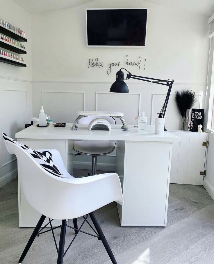 a white desk and chair in a room with a large screen tv on the wall