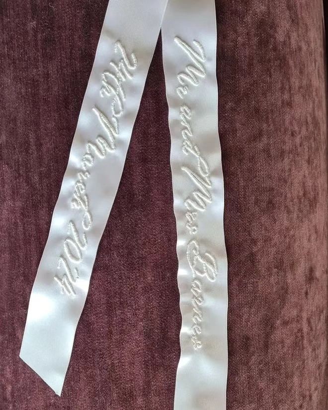 two white ribbons with words on them are attached to a purple velvet chair cushiones