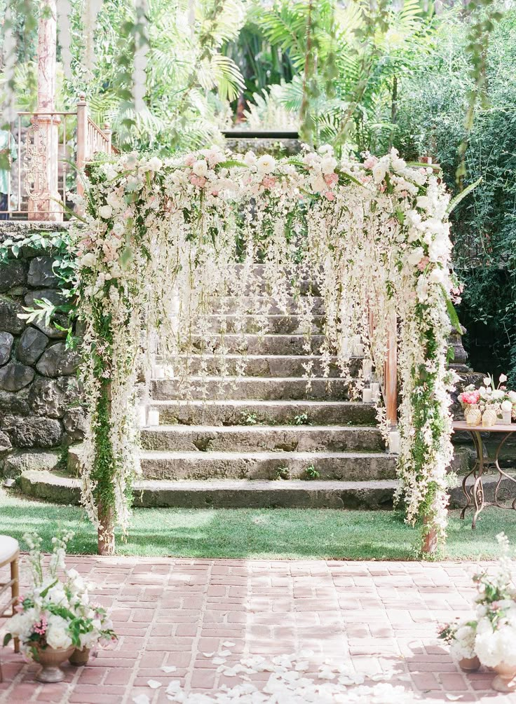 an outdoor wedding setup with flowers and greenery on the steps leading up to the ceremony venue