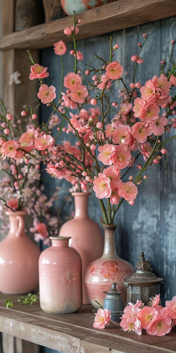 pink flowers are in vases on a shelf next to other vases and containers