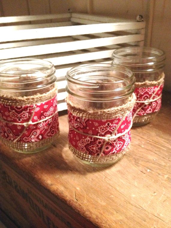 three mason jars are sitting on a wooden table with red and white fabric wrapped around them