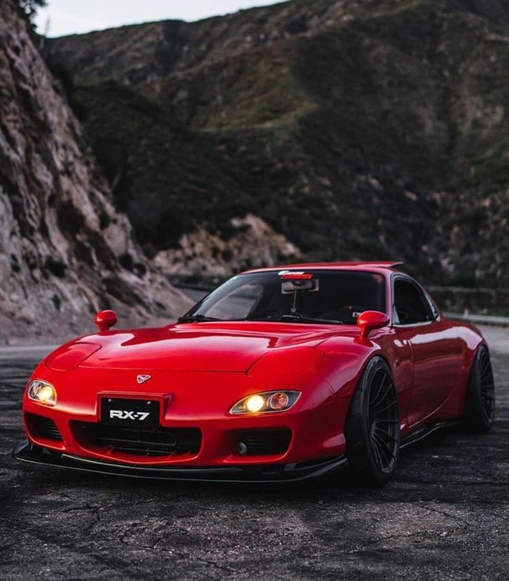 a red sports car parked in front of a mountain