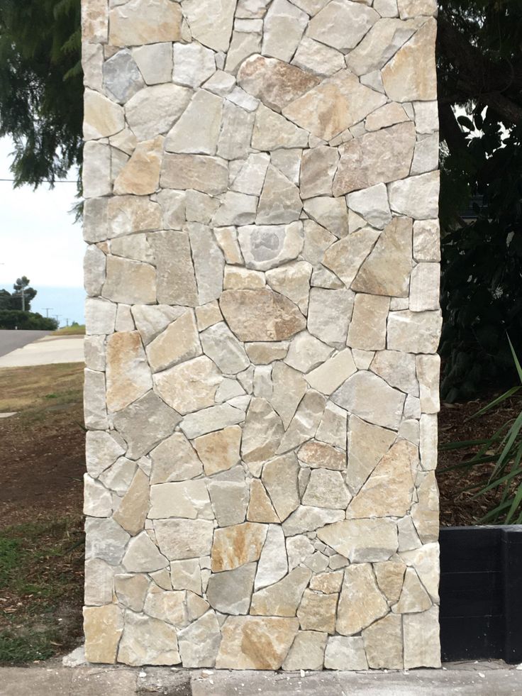 a tall stone pillar sitting next to a lush green field