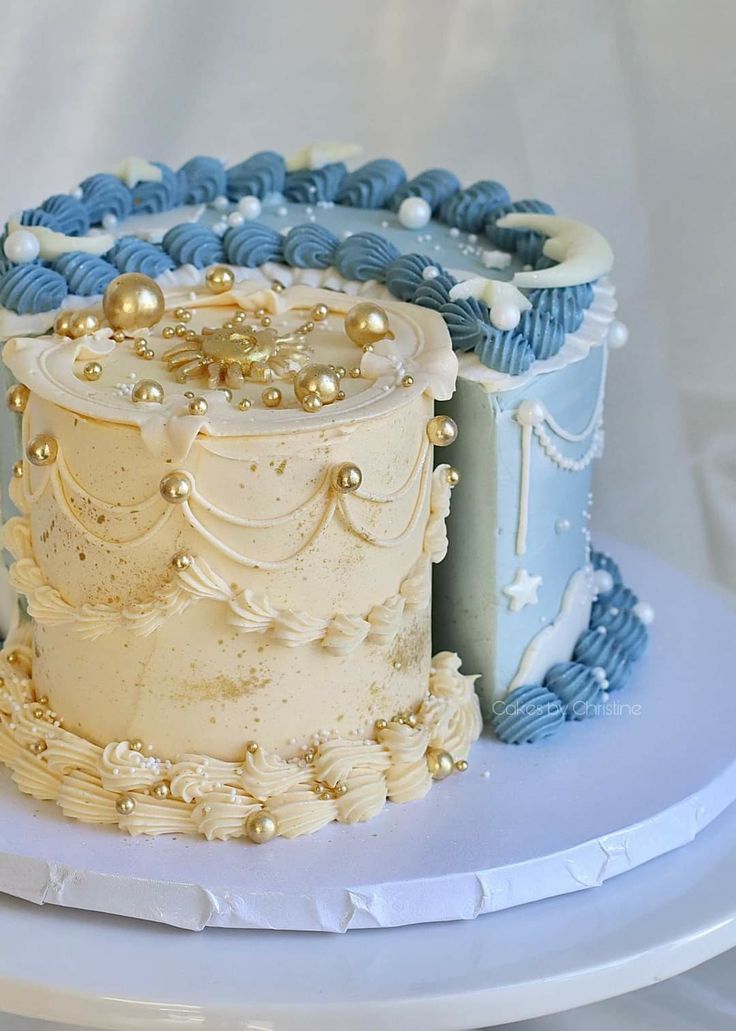 two tiered wedding cake with blue and white frosting on a plate in front of a white backdrop